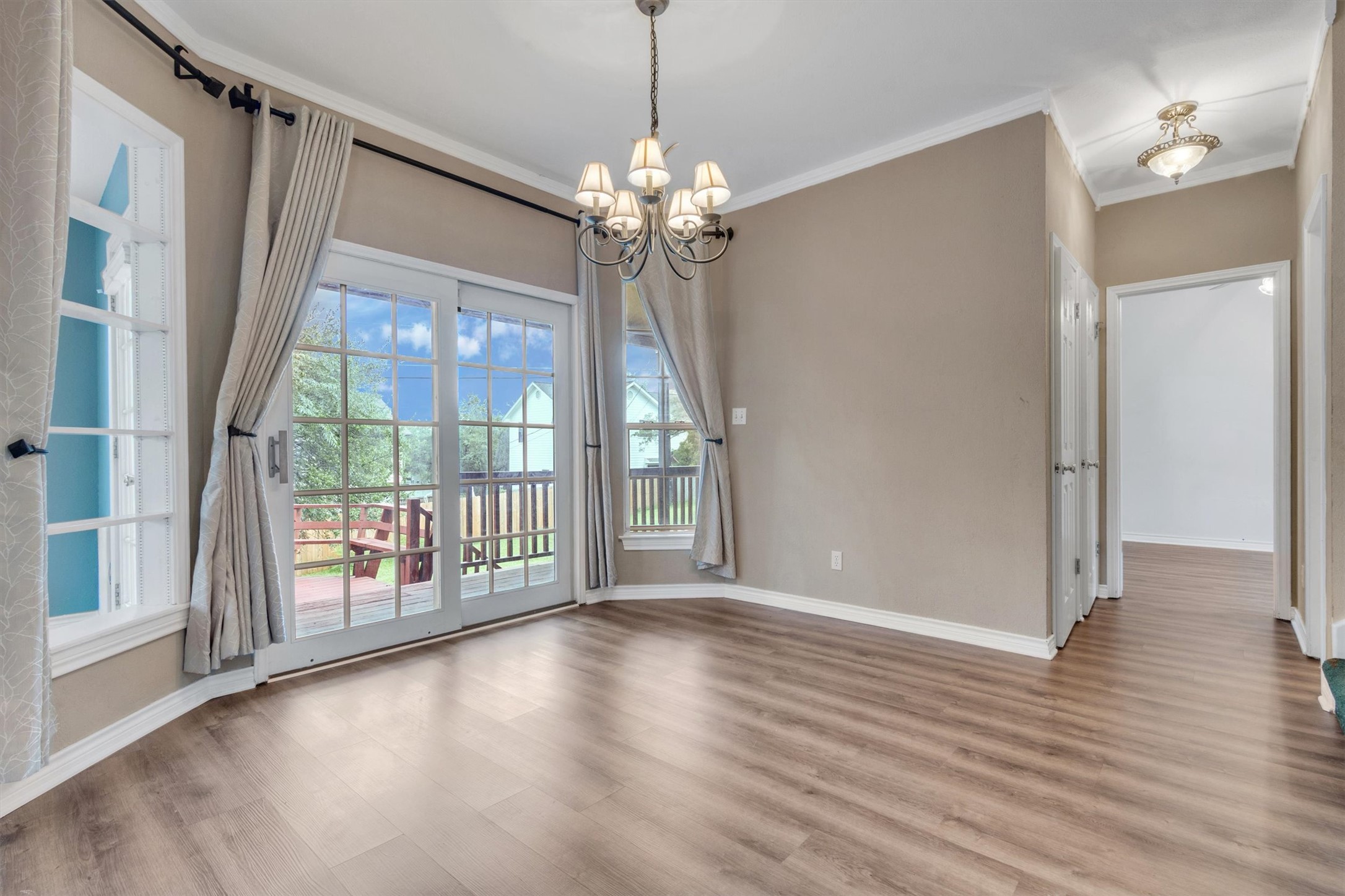 1207 Orlando Road Austin, TX 78733 - Photo 8 of 30 Spacious room featuring wood-finish flooring, a contemporary chandelier, crown molding, and a patio door providing outdoor access