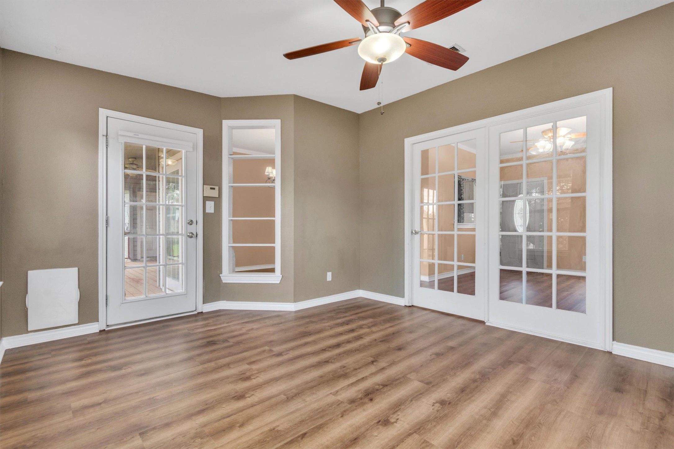 1207 Orlando Road Austin, TX 78733 - Photo 9 of 30 Room featuring wood-finish flooring, two sets of French doors, a tall vertical window, and a ceiling fan with integrated lighting
