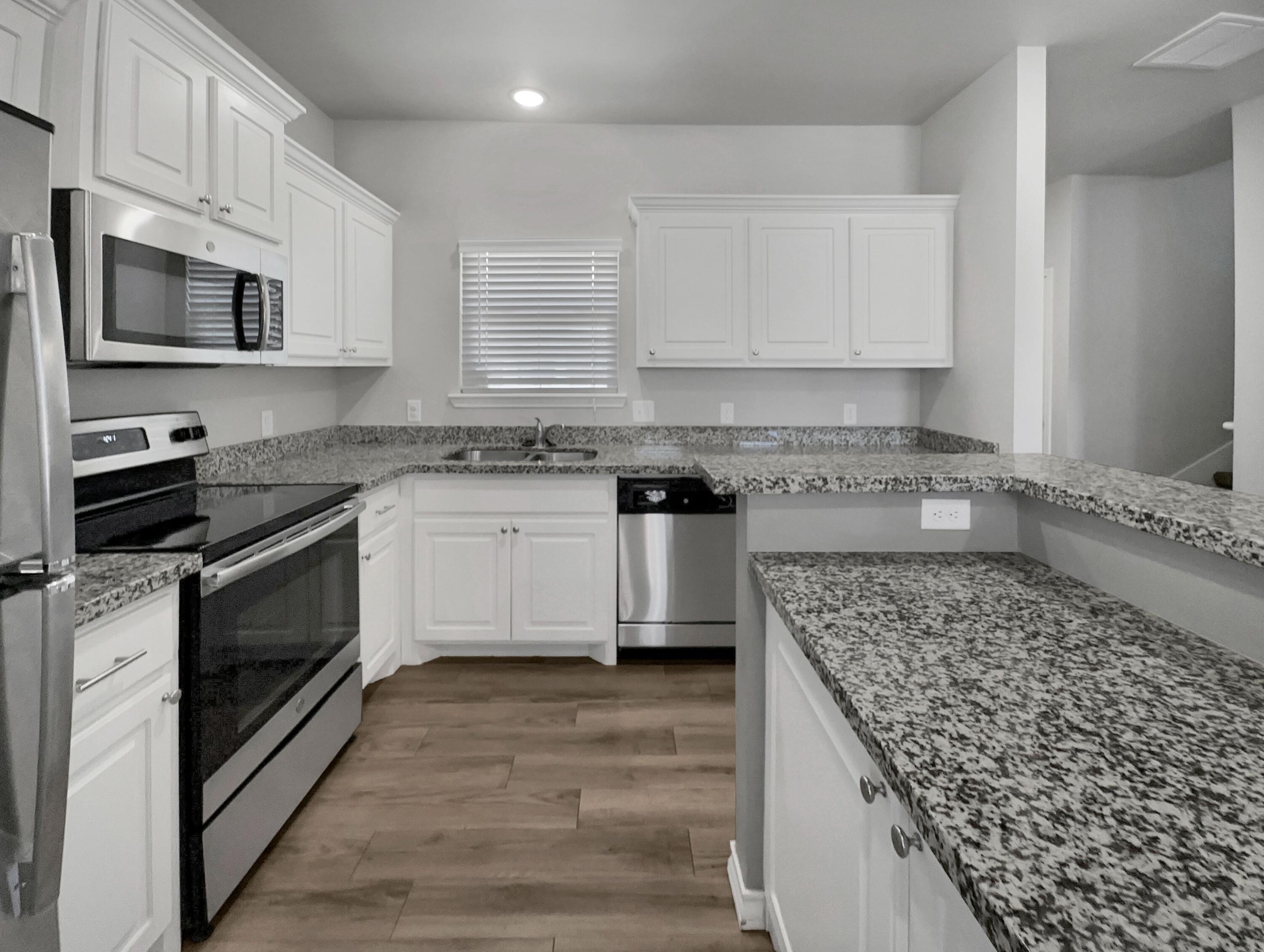 6040 24th Street, Unit 41 Lubbock, TX 79407 - Photo 2 of 12 a kitchen with stainless steel appliances granite countertop a stove a sink and a microwave