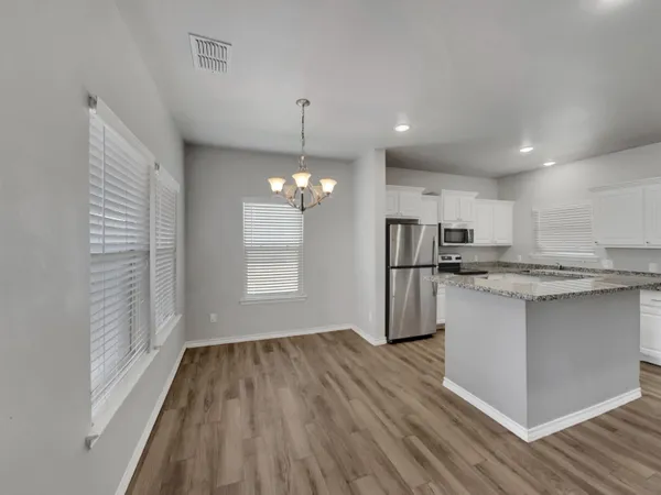 a kitchen with stainless steel appliances granite countertop a refrigerator a oven a sink dishwasher and white cabinets with wooden floor