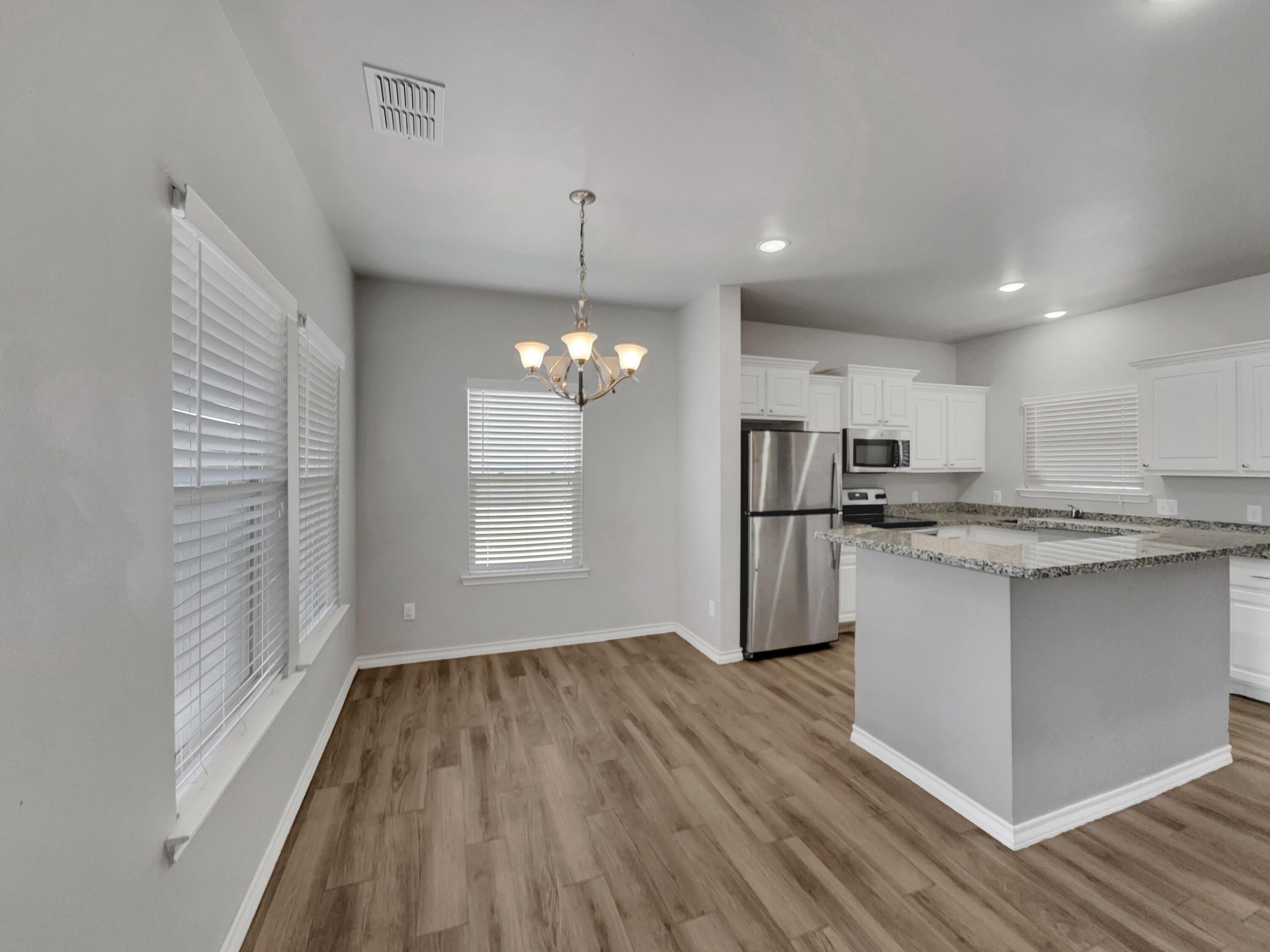 6040 24th Street, Unit 41 Lubbock, TX 79407 - Photo 4 of 12 a kitchen with stainless steel appliances granite countertop a refrigerator a oven a sink dishwasher and white cabinets with wooden floor