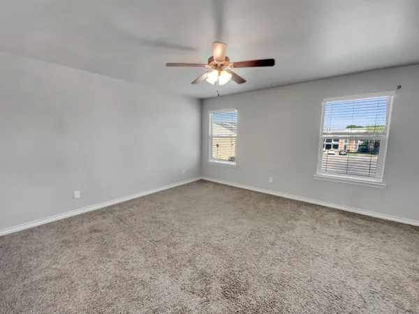 an empty room with windows and fan
