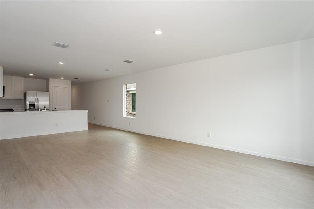 1419 Merlin Blf Street Forney, TX 75126 - Photo 4 of 24 Spacious open-concept living area featuring light wood-finish flooring, recessed lighting, and a kitchen with white cabinetry and stainless steel appliances