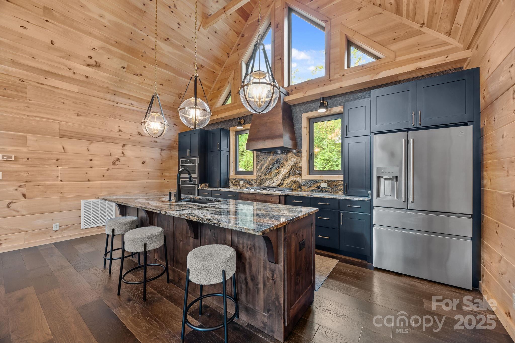 91 Boone Cove Road Zirconia, NC 28790 - Photo 11 of 48 a kitchen with stainless steel appliances granite countertop a stove a refrigerator a oven a dining table and chairs with wooden floor