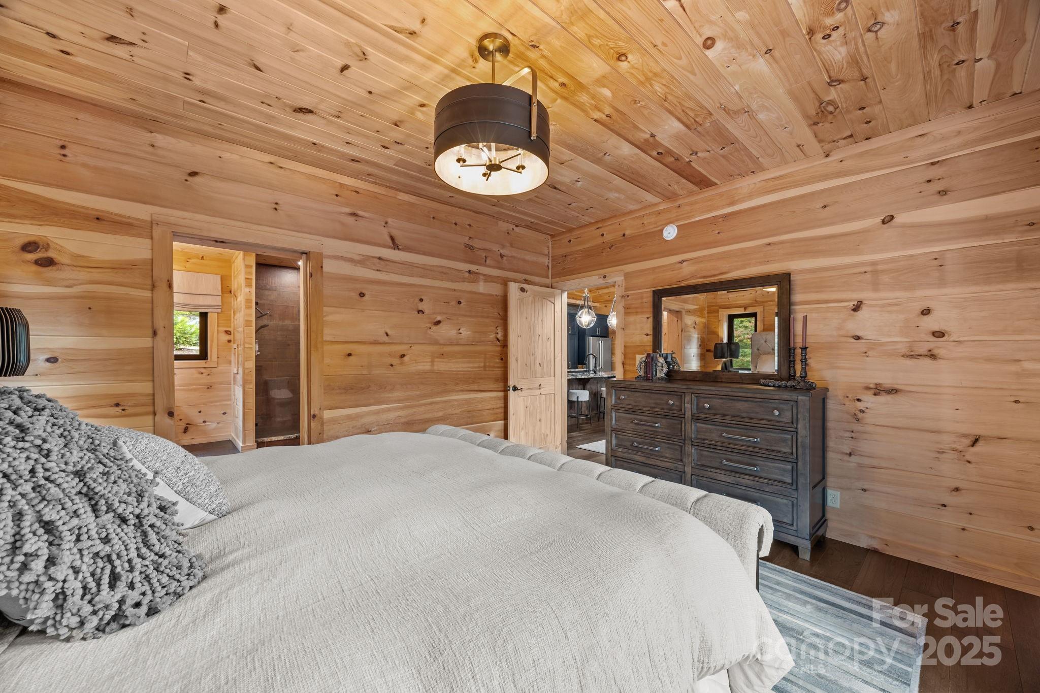 91 Boone Cove Road Zirconia, NC 28790 - Photo 20 of 48 a bedroom with a bed and a chandelier