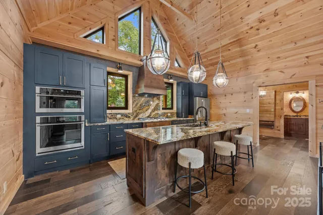 a kitchen with stainless steel appliances granite countertop a stove a refrigerator a oven a dining table and chairs with wooden floor