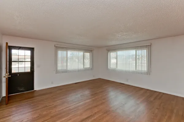 a view of an empty room with wooden floor and a window