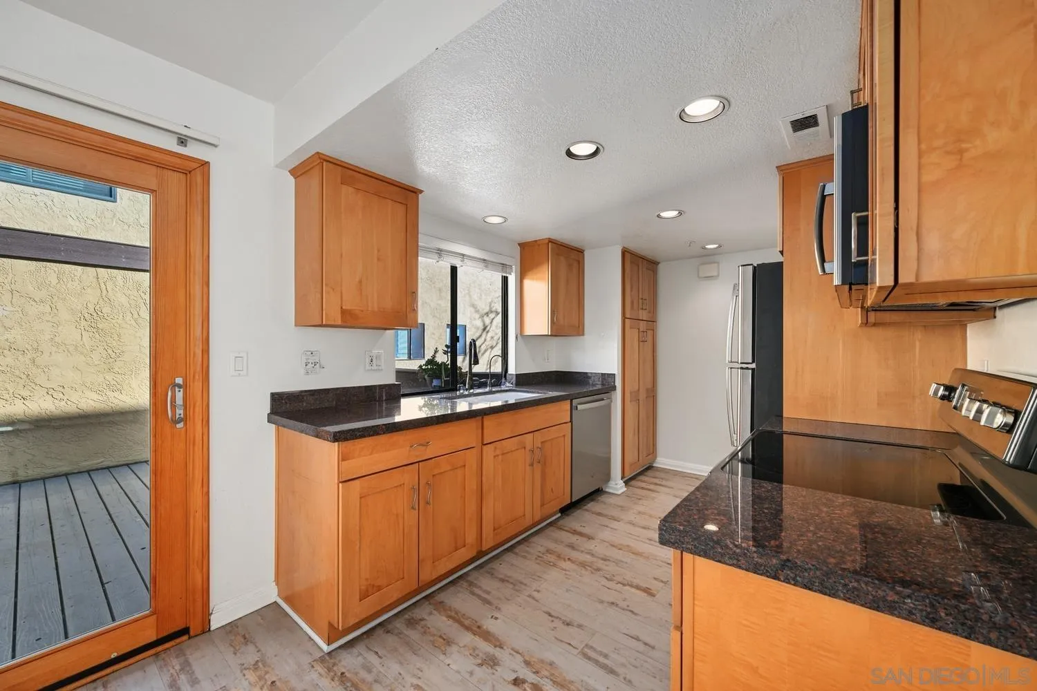 1680 North Coast Highway 101, Unit 30 Encinitas, CA 92024 - Photo 12 of 41 a kitchen with stainless steel appliances granite countertop a sink a stove and a refrigerator