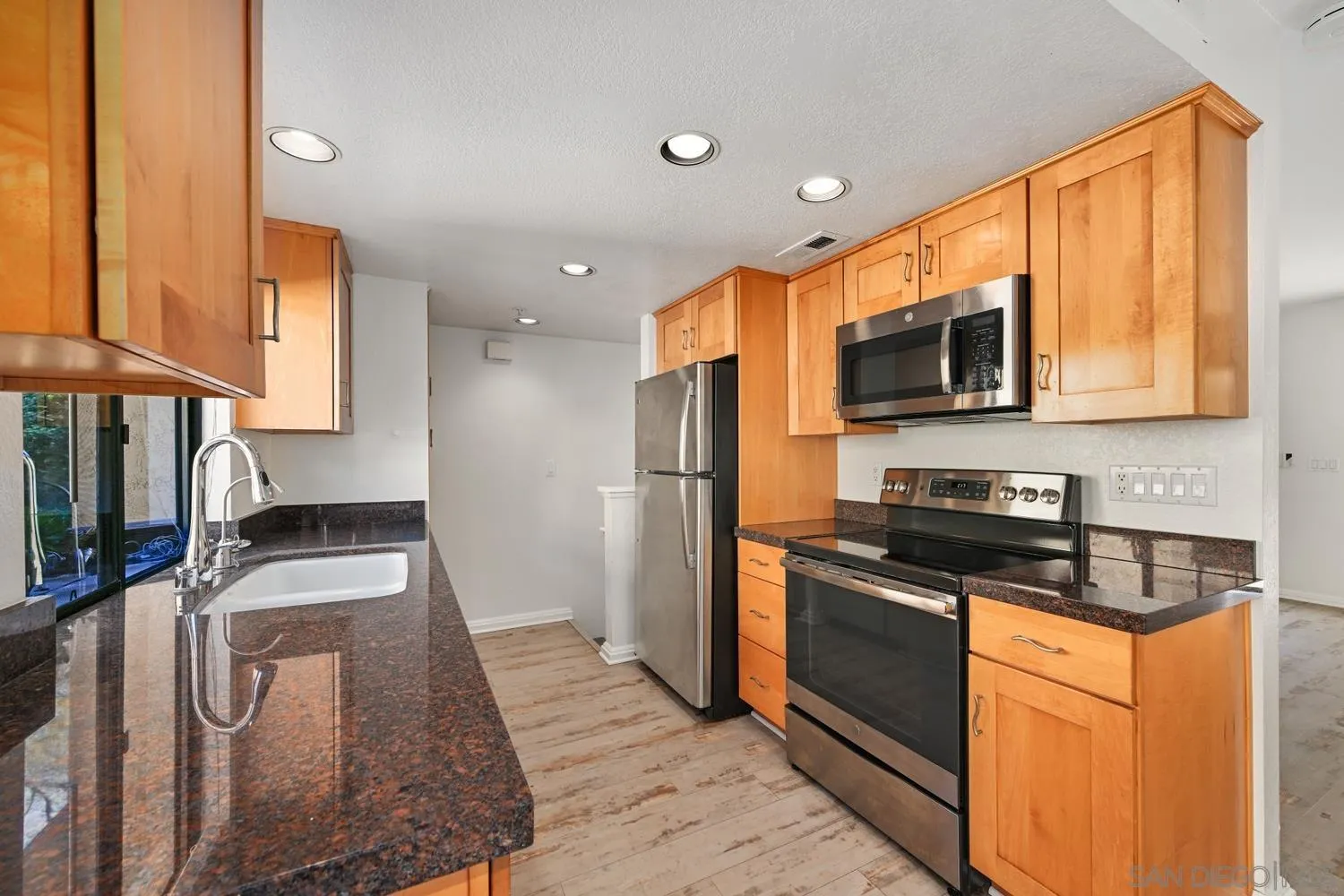 1680 North Coast Highway 101, Unit 30 Encinitas, CA 92024 - Photo 13 of 41 a kitchen with granite countertop stainless steel appliances a stove a sink and a microwave