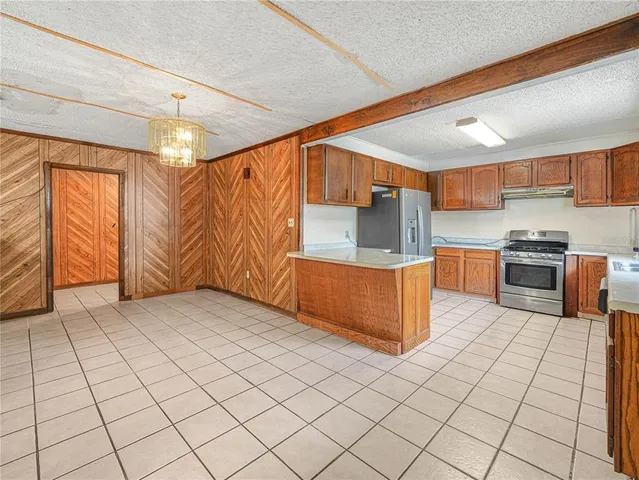 a kitchen with stainless steel appliances kitchen island granite countertop a refrigerator a stove and a sink