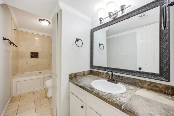 a bathroom with a granite countertop sink a toilet and a mirror