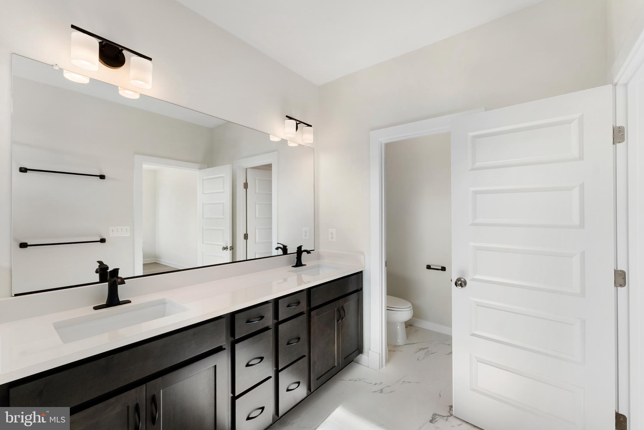 129 Summit Point Boulevard, Unit 11J Bowie, MD 20716 - Photo 32 of 45 a bathroom with a double vanity sink a toilet and a mirror