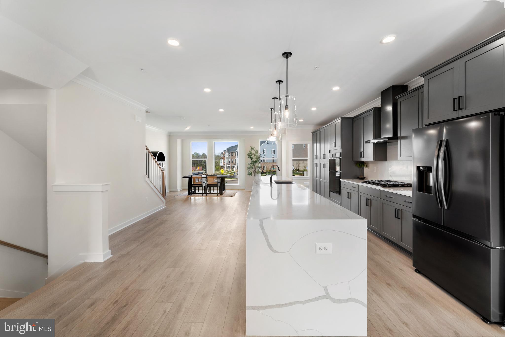 129 Summit Point Boulevard, Unit 11J Bowie, MD 20716 - Photo 10 of 45 a kitchen with stainless steel appliances kitchen island granite countertop a refrigerator a oven a stove and a dining table with wooden floor