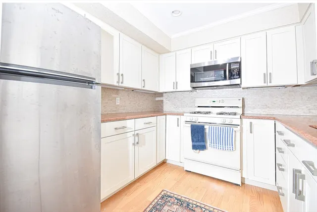 a kitchen with stainless steel appliances white cabinets and a refrigerator