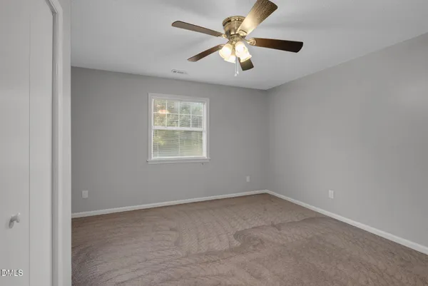 an empty room with a window and a fan
