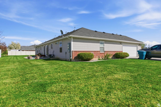 619 East 1st S Street, Unit S Preston, ID 83263 - Photo 3 of 16 Expansive green lawn surrounds this property featuring light-colored siding and a brick-clad foundation
