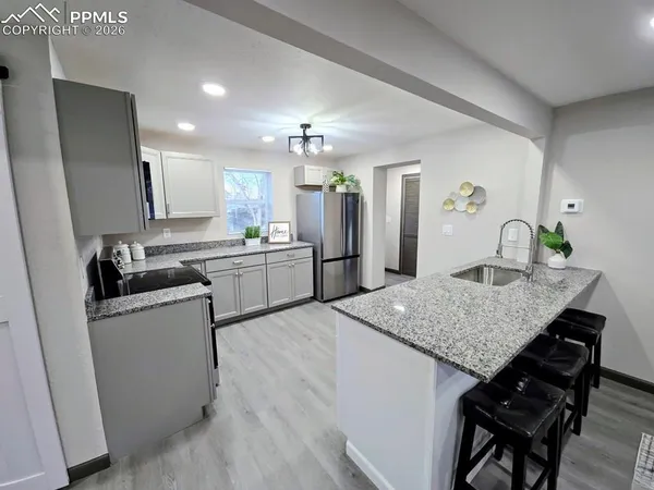 a kitchen with stainless steel appliances granite countertop wooden cabinets a sink dishwasher and a refrigerator