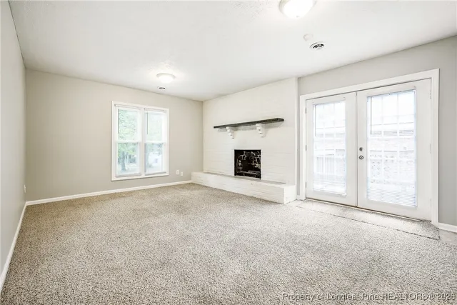 an empty room with windows and fireplace