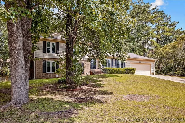 a front view of a house with a garden and tree