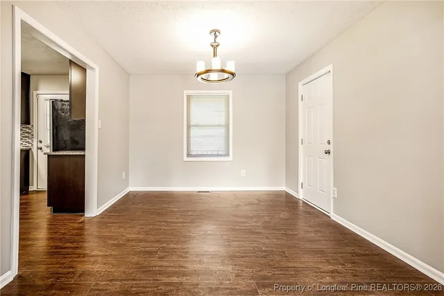 an empty room with wooden floor cabinet and windows