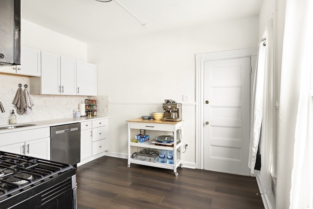 55 Main Street Somerville, MA 02145 - Photo 12 of 28 a kitchen with stainless steel appliances a stove and white cabinets