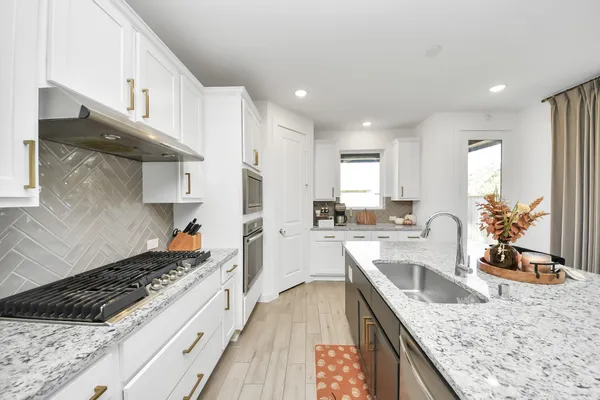 a large kitchen with stainless steel appliances granite countertop a lot of counter space and wooden floor