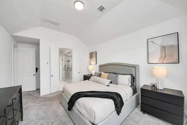 a bedroom with a bed and a lamp on dresser