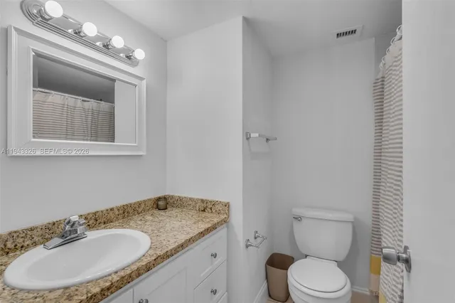 a bathroom with a granite countertop sink a mirror and a toilet