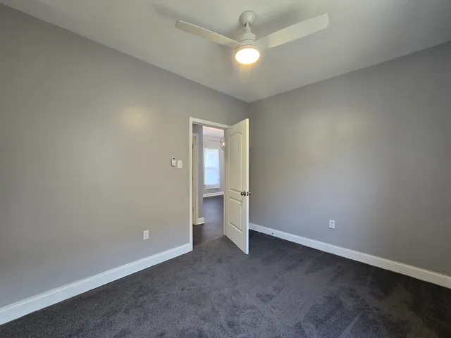 an empty room with a ceiling fan and a window