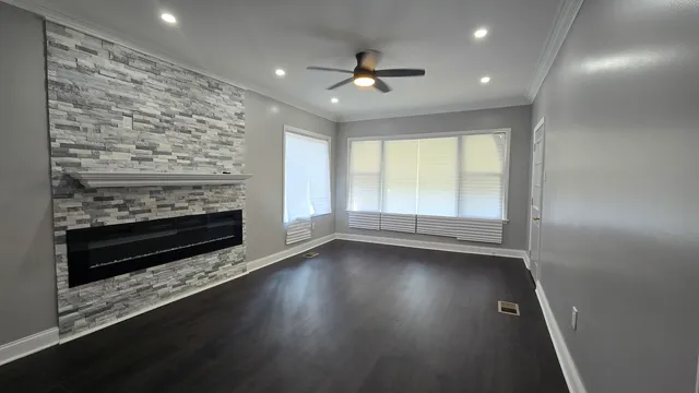 an empty room with wooden floor fireplace and windows