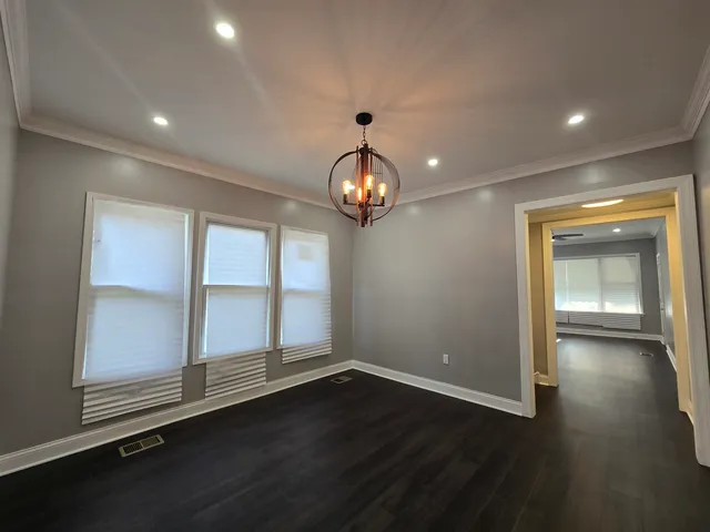 an empty room with wooden floor cabinet and windows