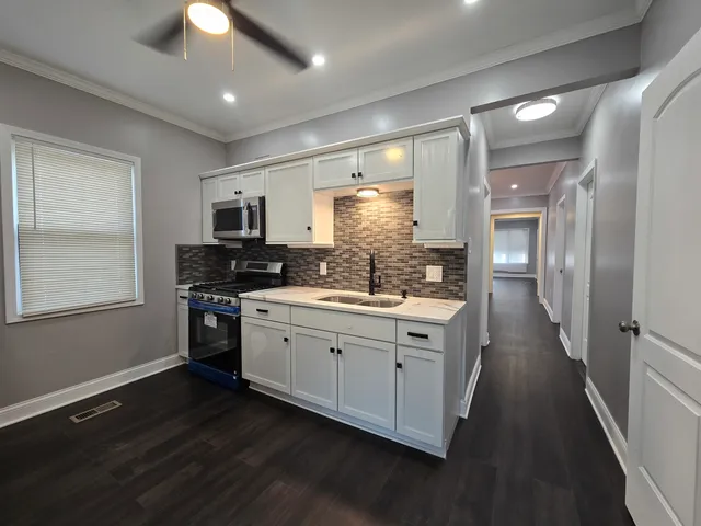a kitchen with granite countertop a sink cabinets and stainless steel appliances