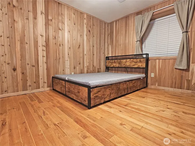 a view of a bedroom with wooden floor and windows