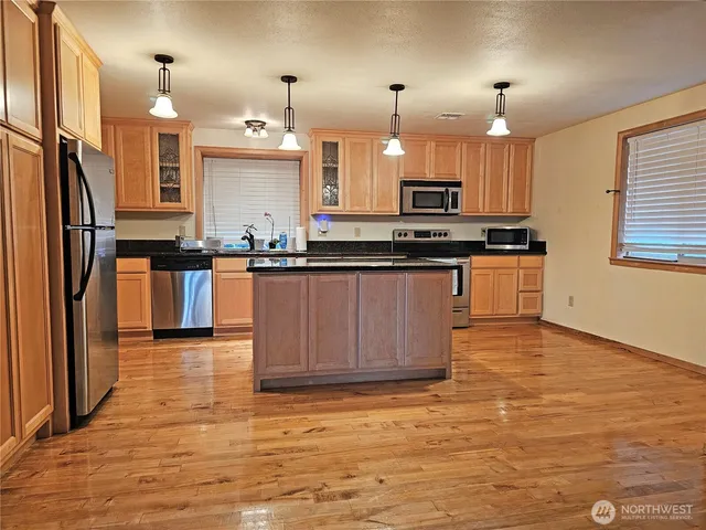 a kitchen with stainless steel appliances granite countertop a refrigerator a sink dishwasher a stove with wooden floor