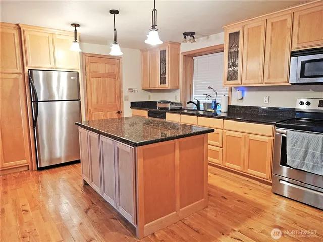 a kitchen with stainless steel appliances granite countertop a sink a stove counter space and cabinets