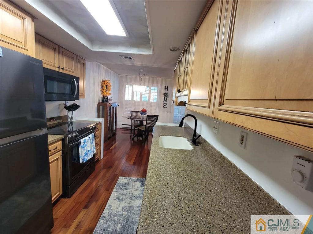 35 Haddon Road, Unit A Monroe Township, NJ 08831 - Photo 6 of 18 a large kitchen with stainless steel appliances granite countertop a stove a sink dishwasher a microwave oven with a dining table and chairs with wooden floor