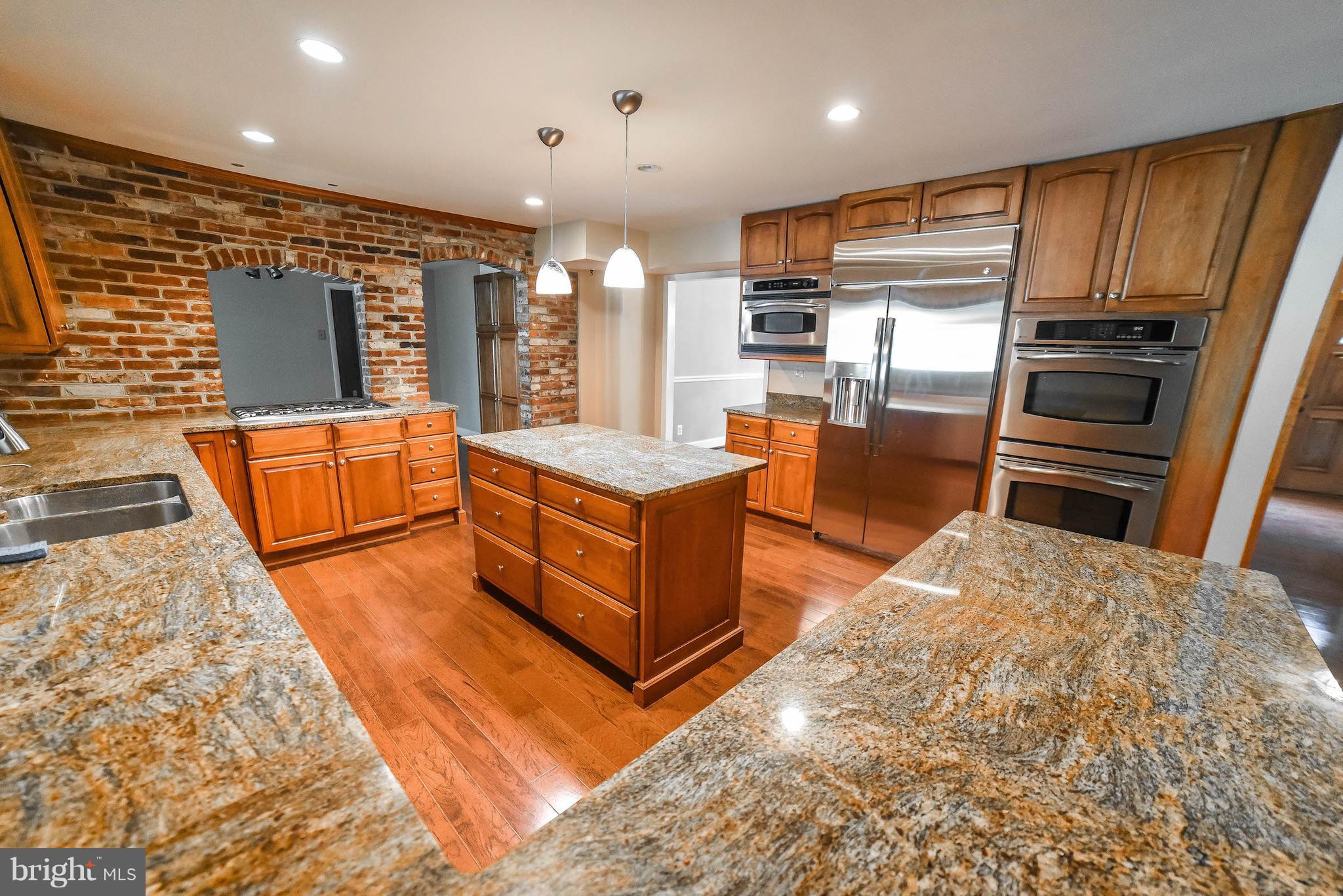 3540 Patuxent Road Huntingtown, MD 20639 - Photo 4 of 29 a large kitchen with stainless steel appliances kitchen island granite countertop a refrigerator and wooden cabinets