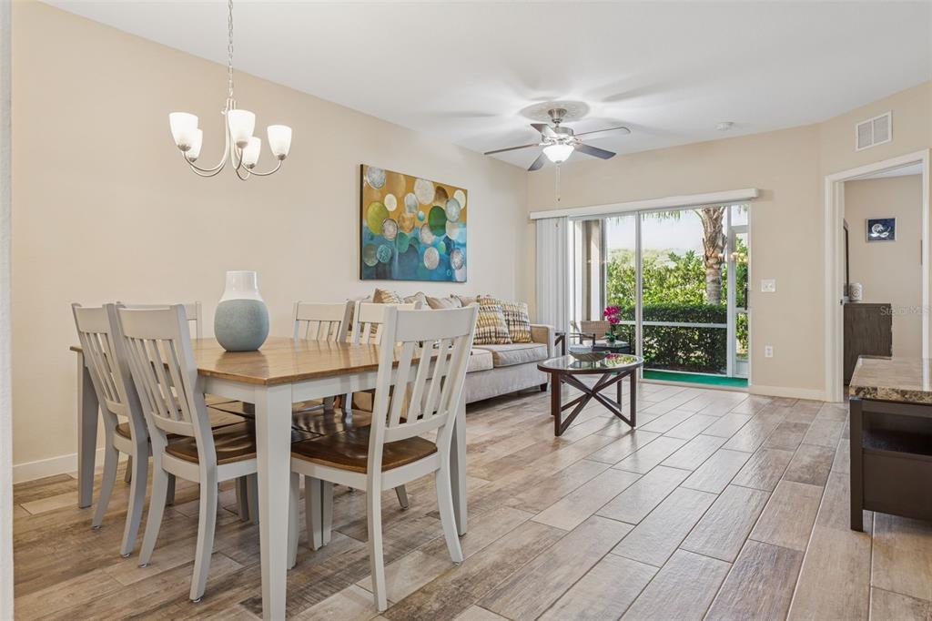 1231 Godavari Way, Unit 101 Wesley Chapel, FL 33543 - Photo 8 of 36 a view of a dining room with furniture a chandelier and wooden floor
