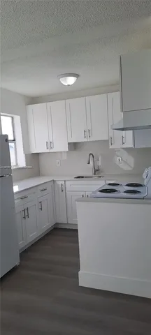 a kitchen with stainless steel appliances granite countertop a sink a stove and white cabinets with wooden floor