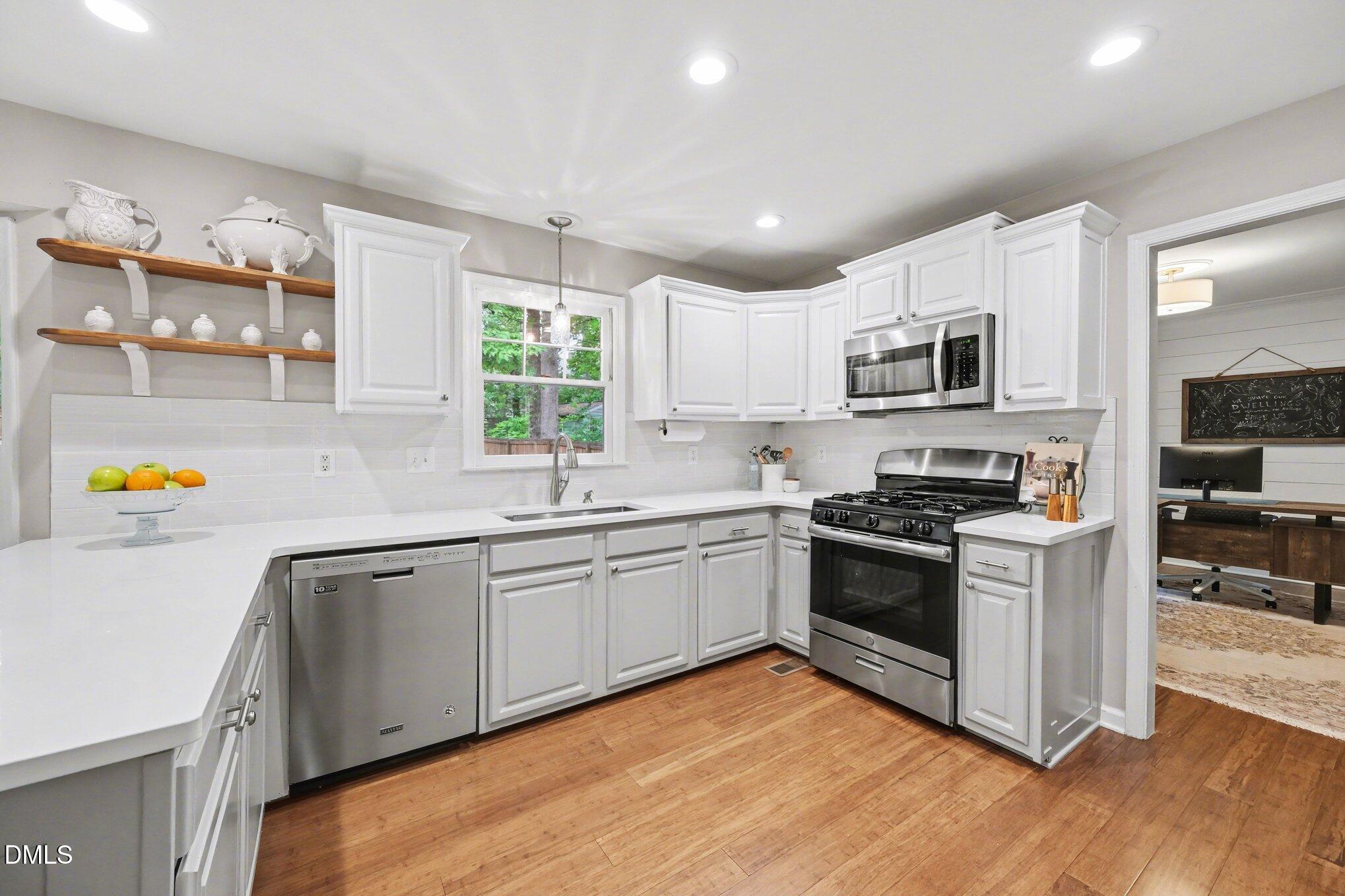103 Leckford Way Cary, NC 27513 - Photo 14 of 49 a kitchen with stainless steel appliances granite countertop a stove top oven a sink dishwasher and white cabinets with wooden floor