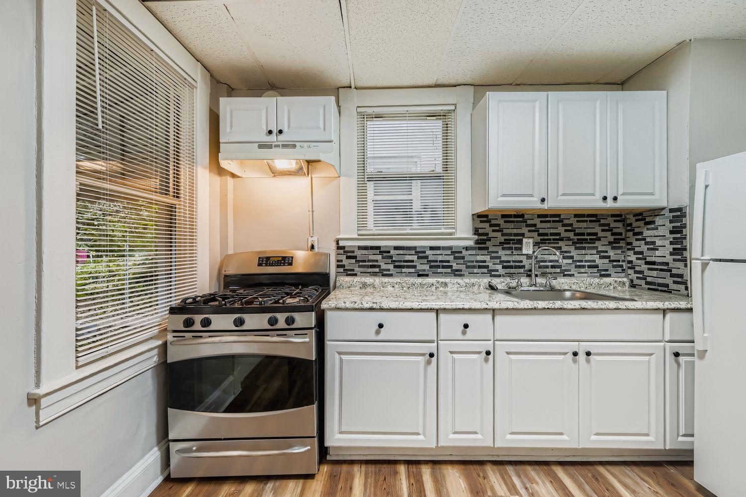 415 Cambria Street Baltimore, MD 21225 - Photo 8 of 17 a kitchen with granite countertop white cabinets and white appliances