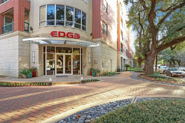 a front view of multi story residential apartment building with yard and sign board