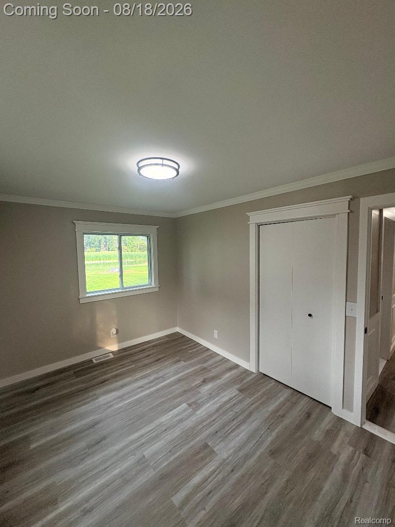32563 Sutton Road New Baltimore, MI 48047 - Photo 36 of 43 Wood-finish flooring, neutral wall tones, window with white trim, bi-fold closet doors, and a flush-mount ceiling light fixture