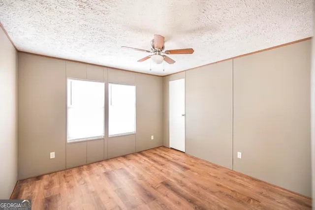 an empty room with windows and fan