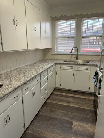 a kitchen with granite countertop white cabinets sink and window