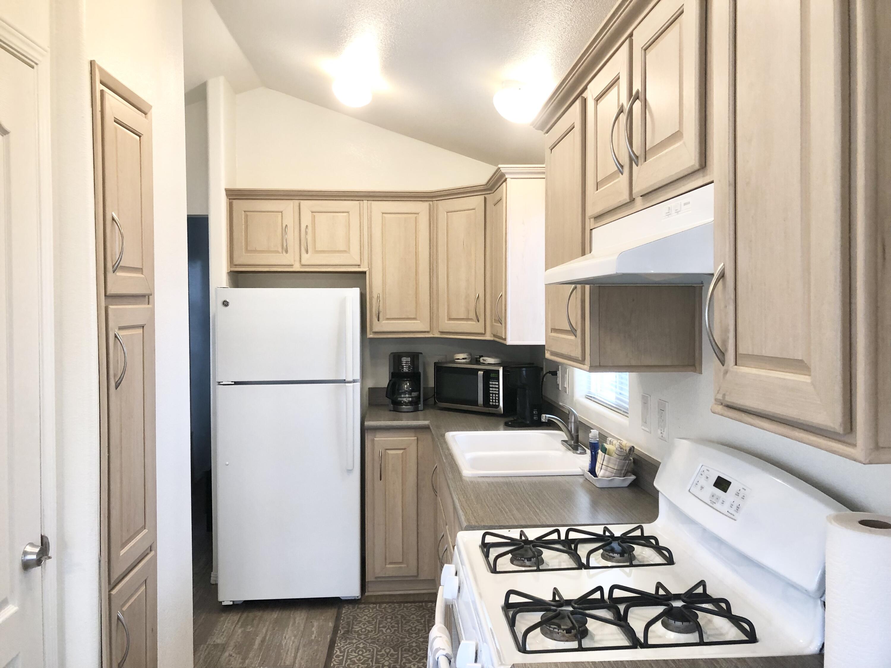 74711 Dillon Road Desert Hot Springs, CA 92241 - Photo 8 of 41 a kitchen with stainless steel appliances granite countertop a refrigerator a stove and a sink with wooden floor