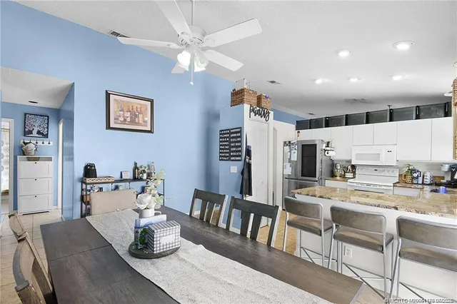 a kitchen with a dining table chairs and white cabinets