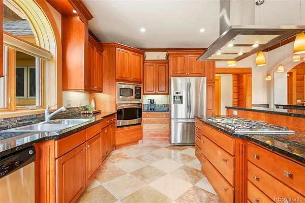 a large kitchen with stainless steel appliances a counter space a sink and a large window