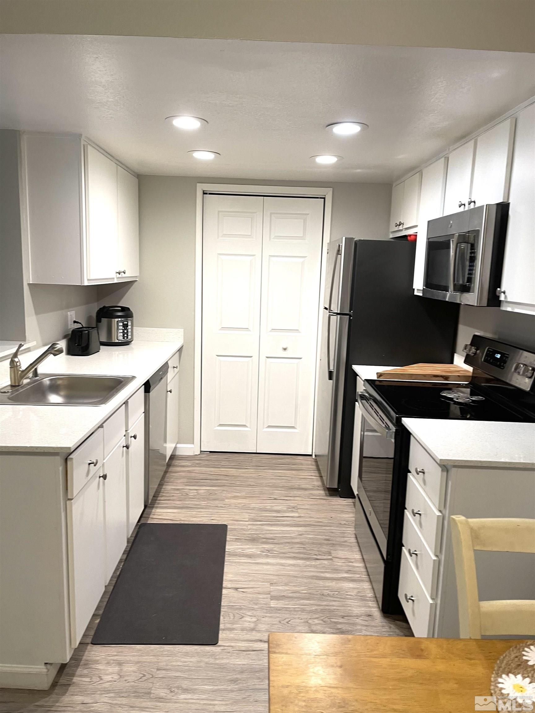 7680 Bluestone Drive, Unit 409 Reno, NV 89511 - Photo 11 of 16 a kitchen with a refrigerator a sink and a stove top oven