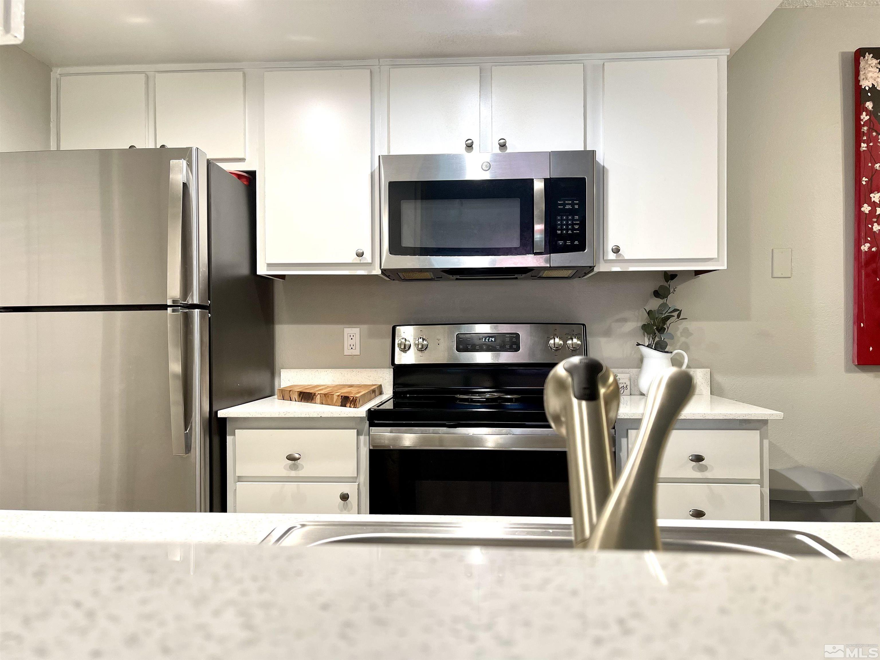 7680 Bluestone Drive, Unit 409 Reno, NV 89511 - Photo 4 of 16 a kitchen with stainless steel appliances a stove a microwave and a refrigerator